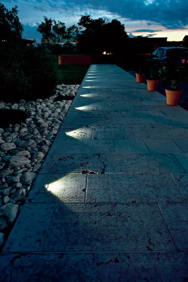 A row of glowing lights illuminating a peaceful sidewalk at night, creating a warm and inviting atmosphere.