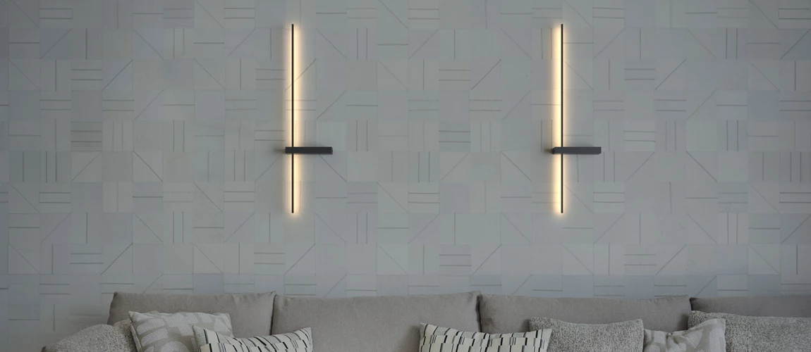 Two vertical wall sconces illuminating geometric-patterned wallpaper over a sofa with cushions.